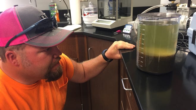 Plant operator Levi Warehime examines sewage to see how fast bacteria is pulling solids out of water in Choteau's new treatment system.