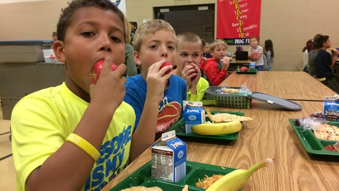 Sunrise School third-grade students Jaylen Reynolds, Emmett Cihlar and Dominic Blish, from left, chomp down on their locally grown apples at lunchtime as part of the third annual Great Apple Crunch, an event held across the Upper Midwest, form Minnesota to Ohio. The Sturgeon Bay School District took part by offering local apples to all students who wanted to join the event. The Great Apple Crunch is held during National School Lunch Week and National Farm to School Month.