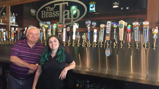 Jessie Rowe III, one of the owners of Brass Tap, and server Ana Cross pose in front of the beer taps at the Mesa location. The craft beer restaurant will open a location in the Gilbert Heritage District in early 2018.