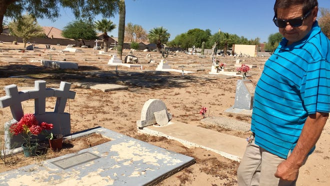 Jose Villela, president of Primeras Familias Campesinas, stands in front of the graves of his relatives, Pedro, Margarita and Manuel Villela at the Goodyear Farms Historic Cemetery.