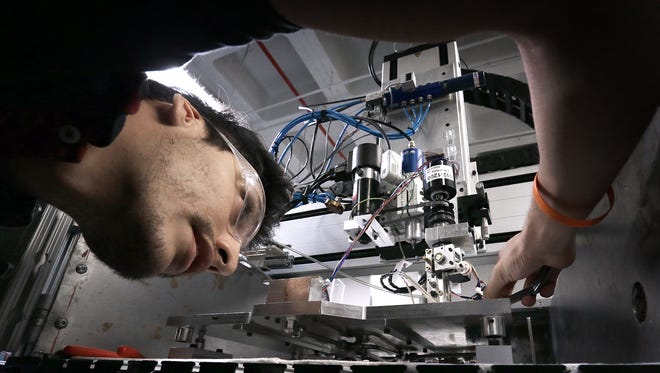 UTEP graduate mechanical engineering student Carlos Acosta works on a machine which injects wire into boards created by 3D printing in the W.M. Keck Center for 3D Innovation.