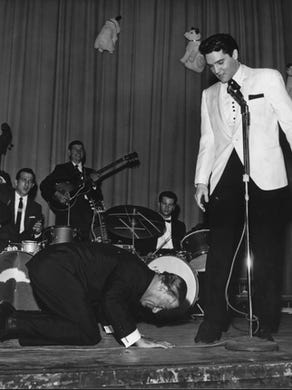 Comedian George Jessel hit the stage in an exaggerated salaam to the King of rock and roll at Elvis' evening performance at Ellis Auditorium Feb. 25, 1961. Jessel, the master of ceremonies, could not make it to the earlier matinee performance because of an airline strike. Elvis Presley Day began earlier with a luncheon honoring the singer at Hotel Claridge. More than $50,000 was raised for charity from the events.