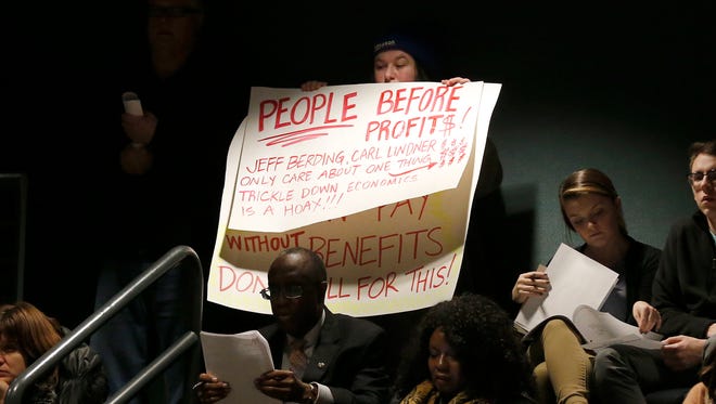 Attendees in opposition of the FC Cincinnati stadium West End location display signs during a Board of Education weekly meeting at the Cincinnati Board of Education in the Avondale neighborhood of Cincinnati on Monday, Feb. 12, 2018.