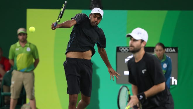 Rajeev Ram (USA) hits a backhand as Brian Baker (USA) looks on against Gael Monfils (FRA, not pictured) and Tsonga Jo-Wilfried (FRA, not pictured) during the men's doubles in the Rio 2016 Summer Olympic Games at Olympic Tennis Centre.