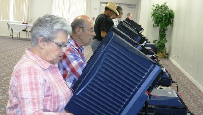 Shirley, left, and Vaughn Silva of Yerington stand at the electronic voter booths in Yerington Tuesday, along with several others, casting their ballots for the 2014 Lyon County primary election, deciding who would advance to the General Election ballot.