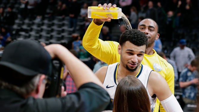 Nuggets forward Darrell Arthur  pours water on the head of Jamal Murray as he is interviewed after the game against the Bucks.