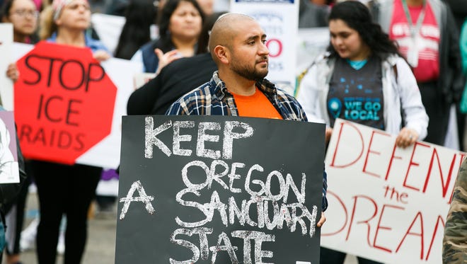 Lupe Garcia holds a sign calling for Oregon to remain a sanctuary state at a May Day rally on Tuesday, May 1, 2018 at the Oregon State Capitol. May Day, also known as International Workers' Day, has evolved from focusing on workers' rights to include immigrant rights. 