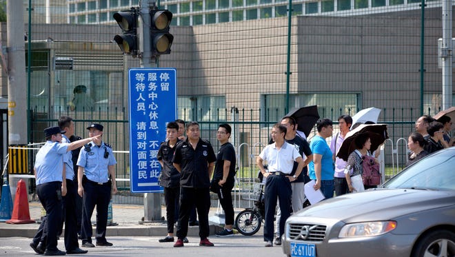 Chinese security personnel stand outside the U.S. Embassy, in the background, after a reported blast occurred nearby in Beijing, Thursday, July 26, 2018.