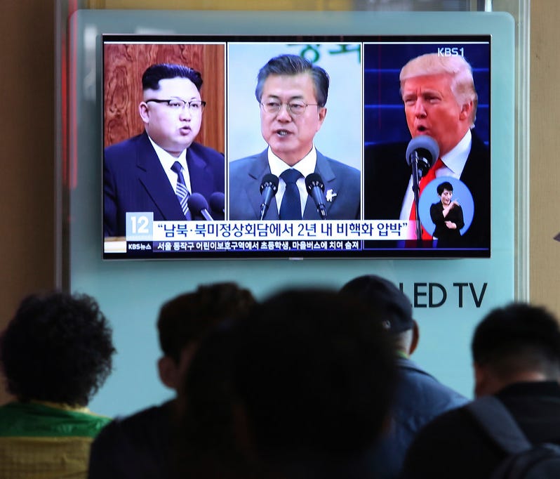 People watch a TV screen showing file footage of President Trump, right, South Korean President Moon Jae-in and North Korean leader Kim Jong Un, left, in Seoul, South Korea, on April 18.