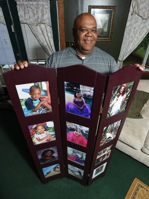 Pastor Keith Wyatt with pictures of some of the more than 200 children that have entered the Wyatt family's lives. From the birth of his two sons, to the adoption of his three daughters, fostering dozens and taking custody of more than 60, the Wyatt household is always full.