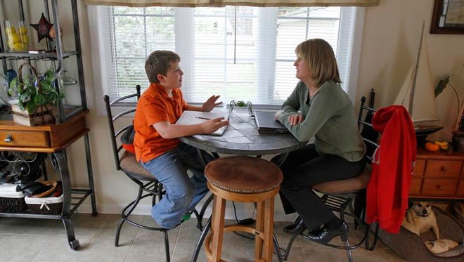 Karen LaLonde sits with son Jake, 10, as he works on his math homework in their Brighton home Thursday, Oct. 24, 2013.