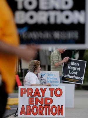 In this Oct. 29, 2013 file photo, Dottie and Tom Knodell, opponents of abortion, hold signs outside a Planned Parenthood Clinic, in San Antonio, Texas.