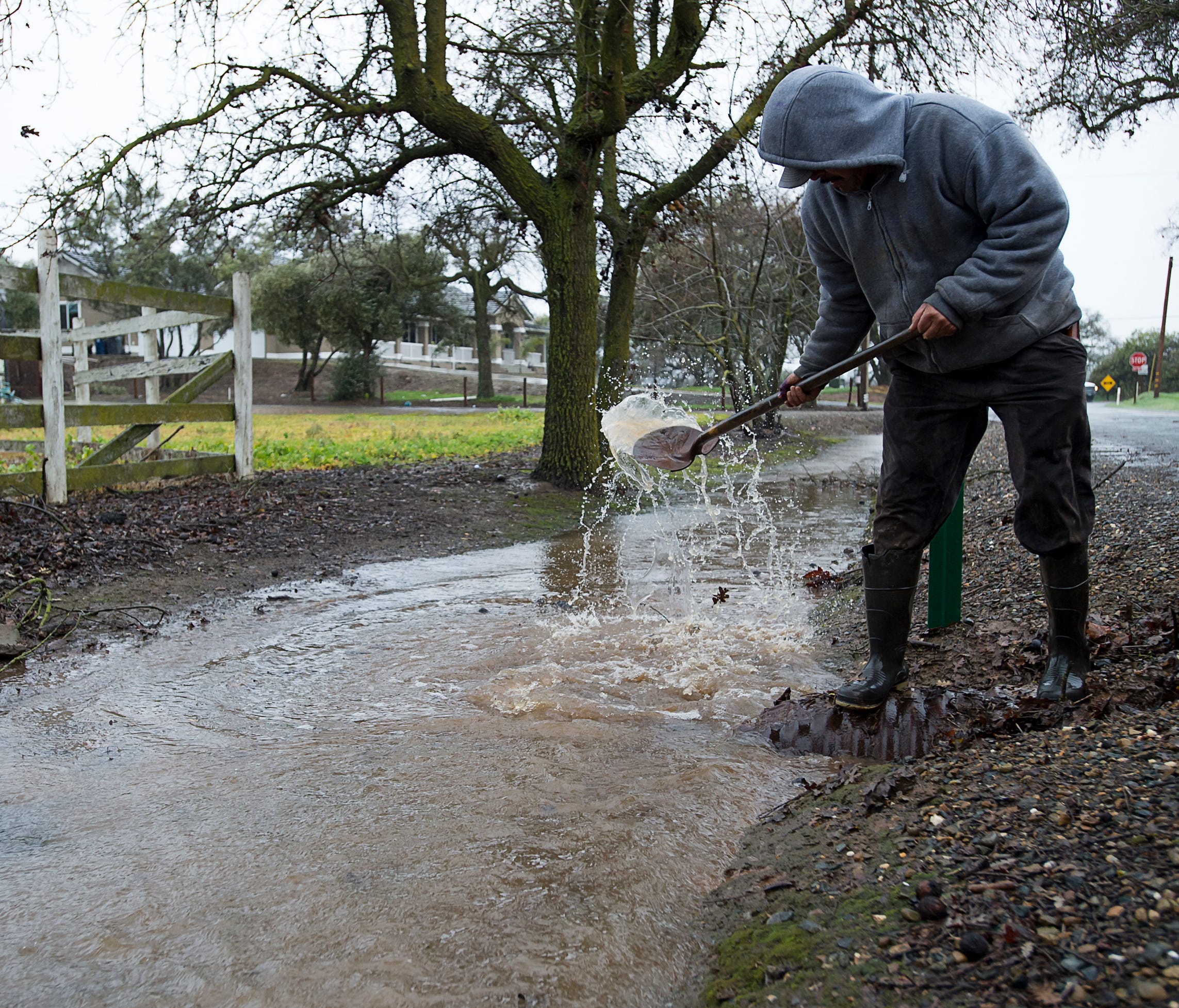 Jose Flores clears storm drains during a storm on Sunday, Jan. 8, 2017, in Wilton, Calif.