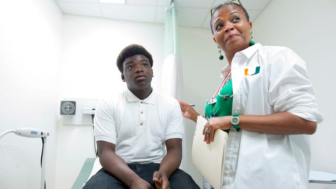Dr. Marie-Denise Gervais gets ready to examine Amos LeClerc at a clinic in a Miami high school. With Florida's medicaid privatization program in its first month, insurers are focusing on children and teens.