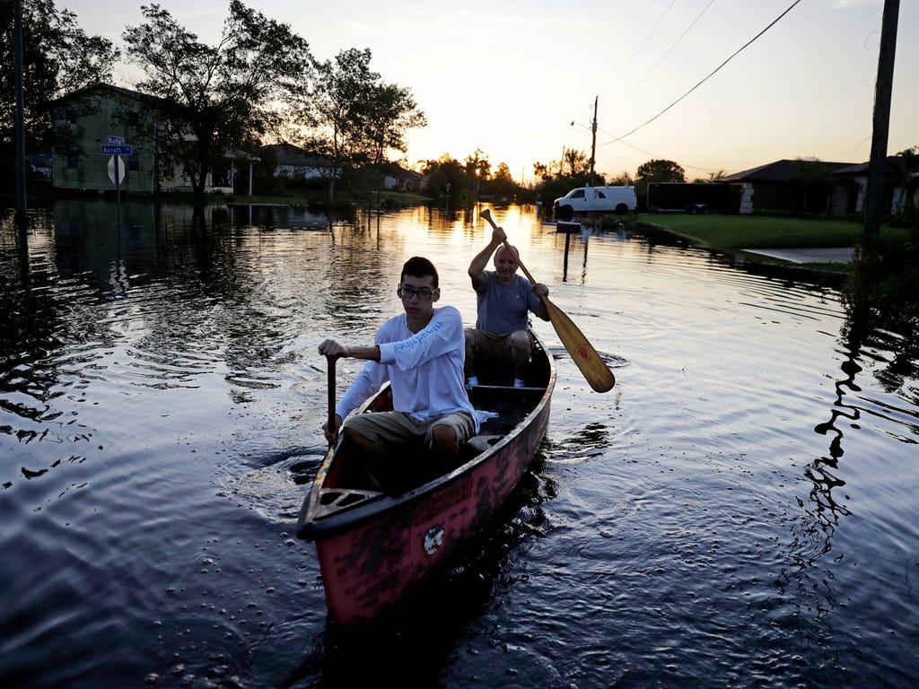 Pierre Ghantos, rear, and his son Nathan paddle though their flooded neighborhood in the aftermath of Hurricane Irma in Fort Myers, Fla., on Sept. 12, 2017.