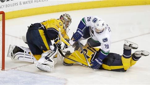 Nashville Predators goalie Pekka Rinne (35), of Finland, collides with defenseman Anton Volchenkov, of Russia, bottom right, and Vancouver Canucks left wing Chris Higgins, top right, in the third period of an NHL hockey game Tuesday in Nashville. Rinne left the ice after the play.