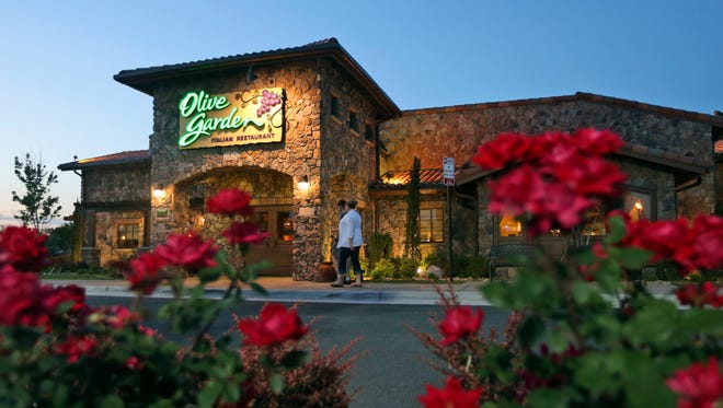 In this May 22, 2014 photo, patrons enter an Olive Garden Restaurant in Short Pump, Va. Olive Garden is hurting itself by piling on too many breadsticks, according to an investor that's disputing how the restaurant chain is run. (AP Photo/Steve Helber)