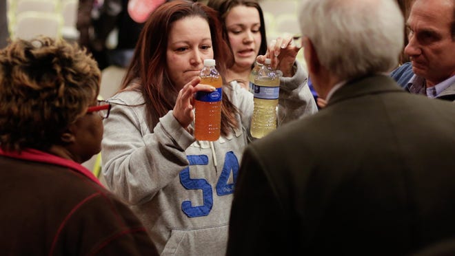 LeeAnne Walters, 36, of Flint shows water samples from her home to Flint emergency manager Jerry Ambrose on Wednesday after city and state officials spoke during a forum that addressed growing health concerns about the drinking water.