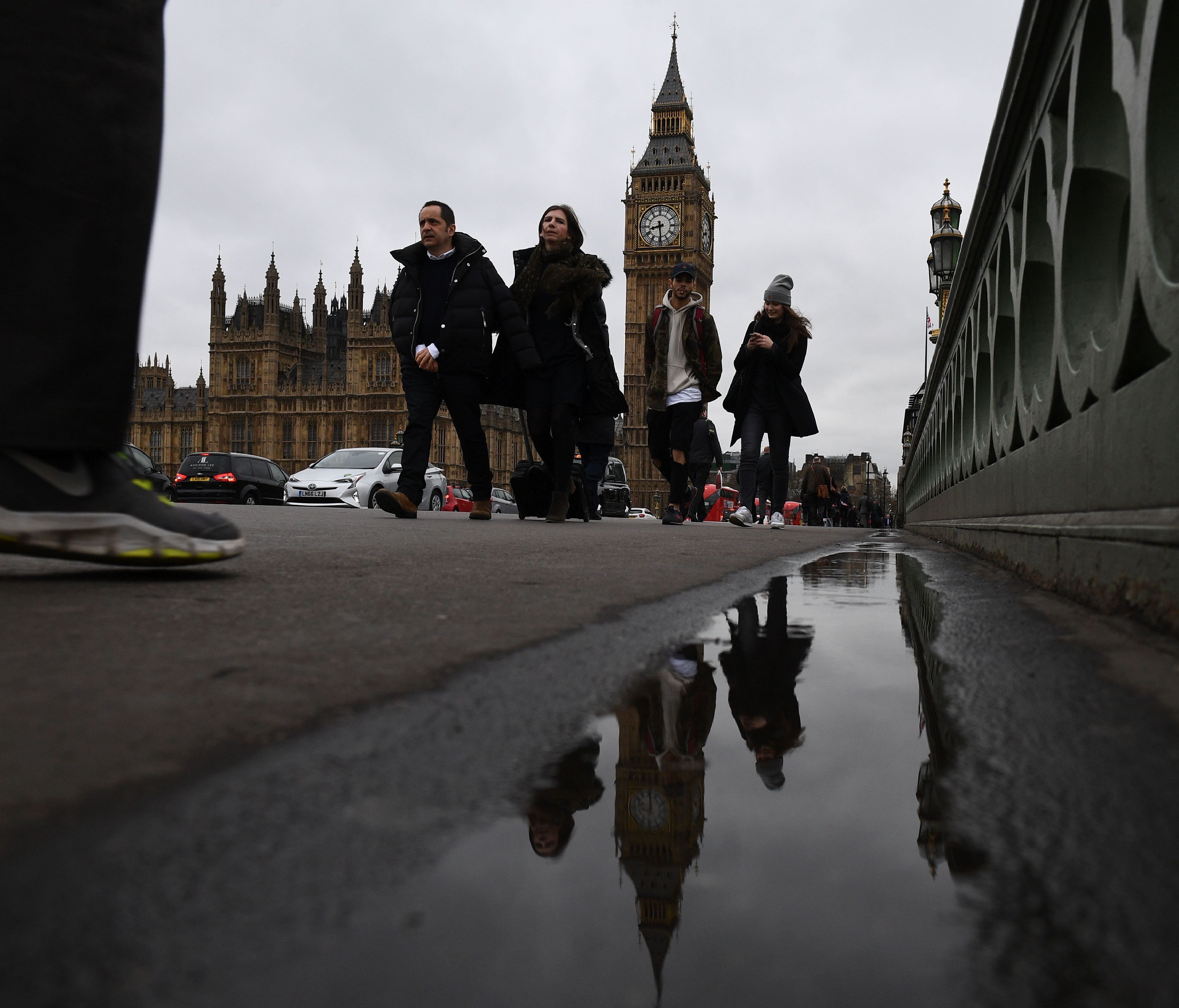 Commuters walks over Westminster bridge by the Houses of Parliament in central London on March 29, 2017.