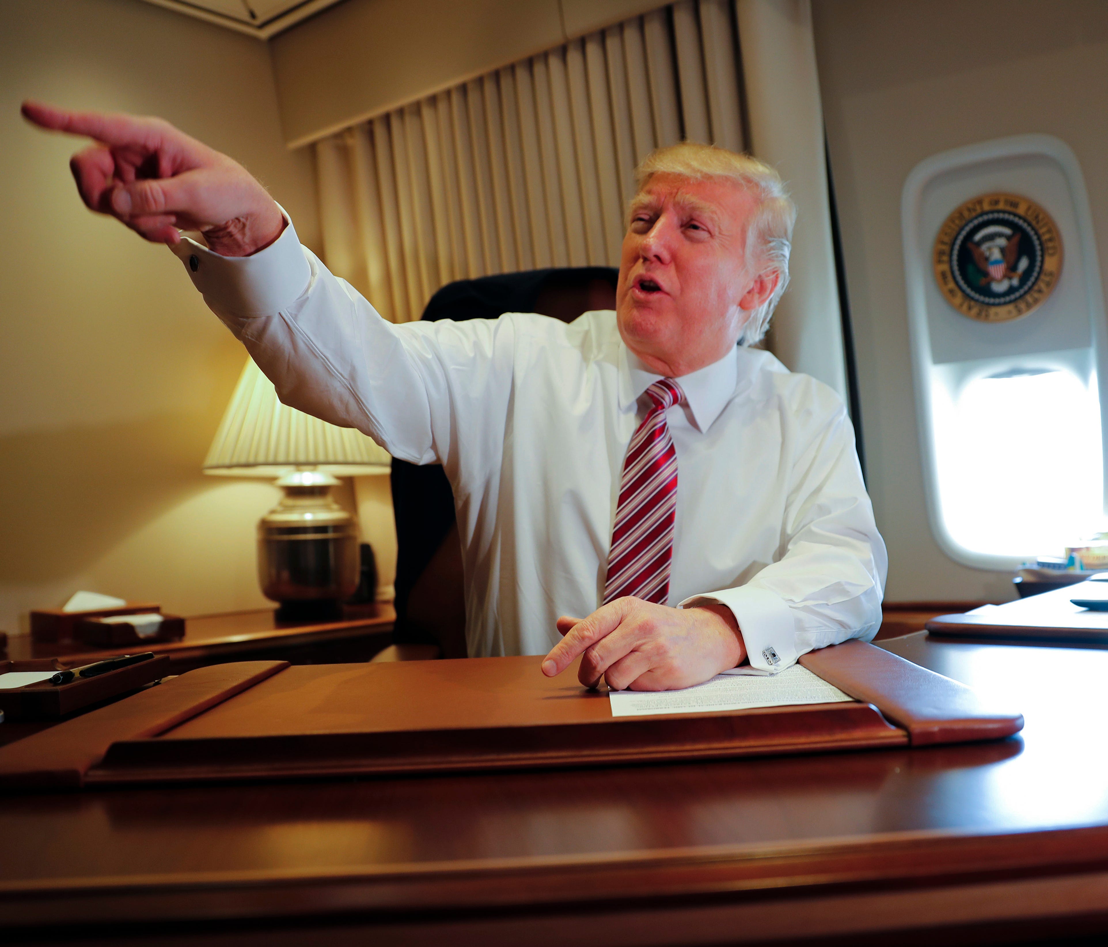 Trump points toward members of the media while seated at his desk on Air Force One upon his arrival at Andrews Air Force Base on Jan. 26, 2017.