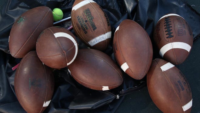 Footballs lie in an empty bag before the start of a high school football game.