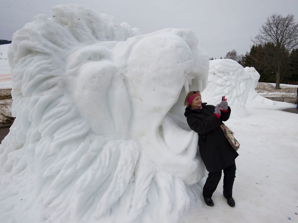A woman makes a selfie in the mouth of a lion snow sculpture \