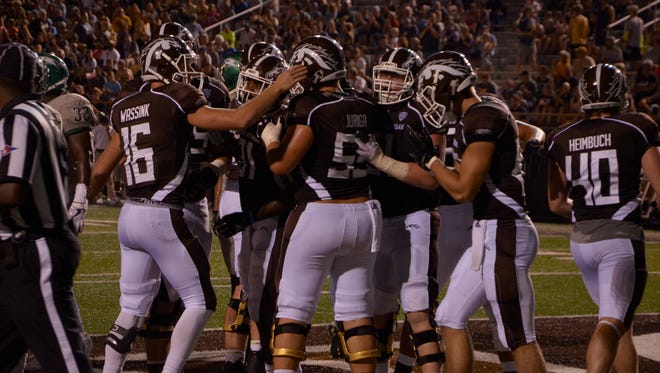 Western Michigan quarterback Jon Wassink (16) and the offensive line celebrate with running back Jarvion Franklin after his 1-yard touchdown run against Wagner on Saturday at Waldo Stadium in Kalamazoo.