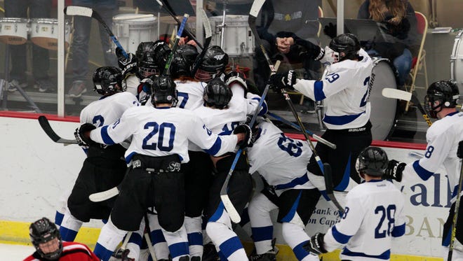 Waukesha players mob  Garrett Wilderman along the boards after his game-winning overtime goal in a semifinal of the WIAA state boys hockey tournament March 3 in Madison.