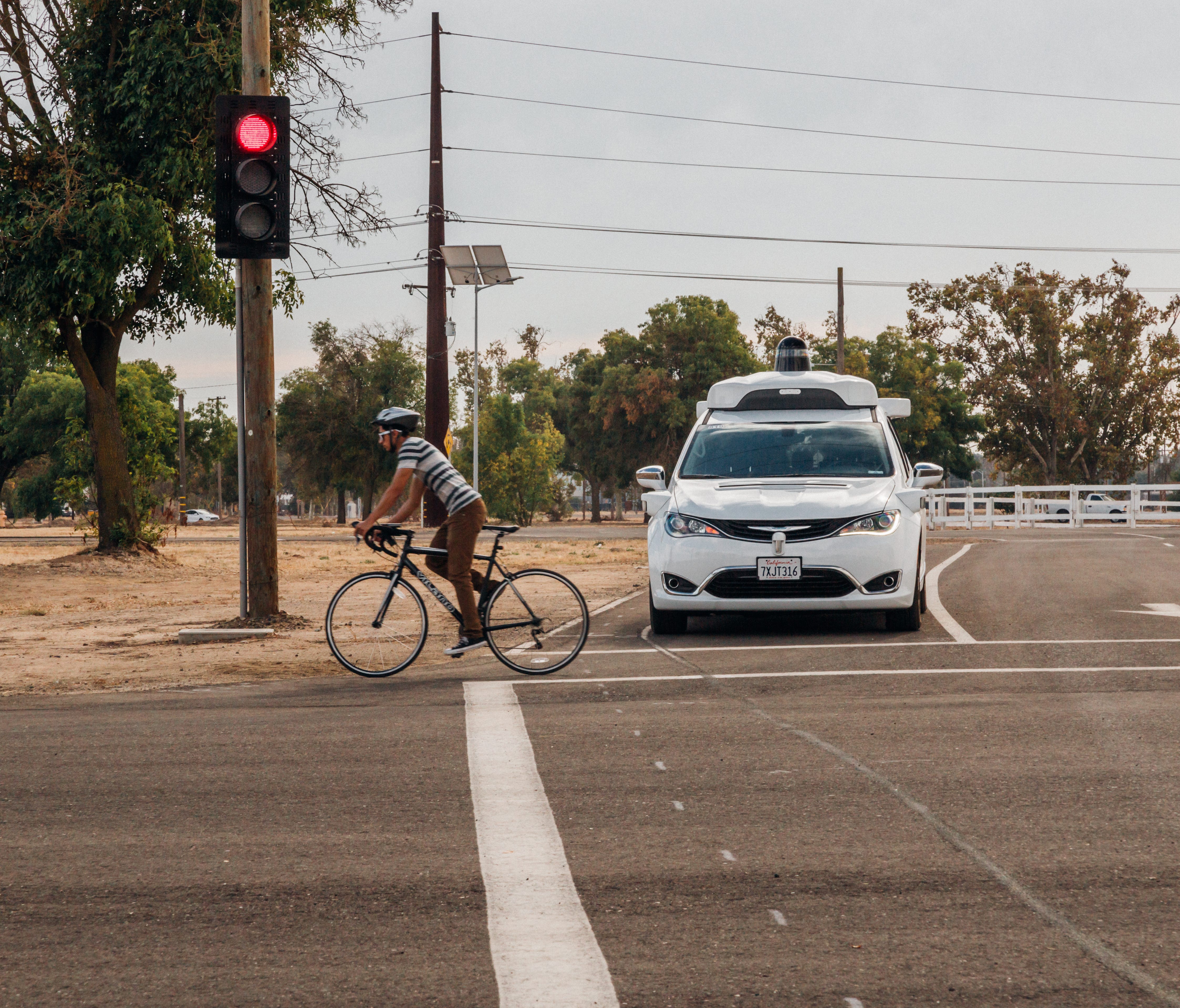 A Waymo self driving minivan stops for a cyclist at the company's private test facility in central California.