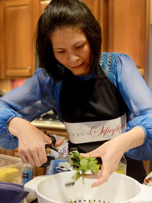 Quynh Shannon, wife of Jackson Symphony Conductor Peter Shannon, prepares the greens for a beef marinade salad during a private dinner for symphony supporters Tuesday at the home of Carl Kirkland.