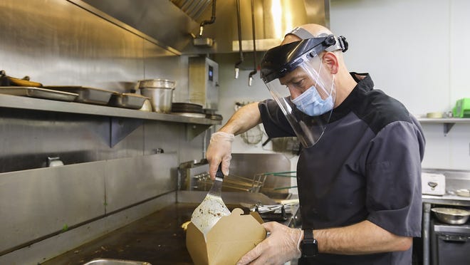 Wearing a mask, face shield and gloves, Joe Deagle, part-owner of Deag's Diner in Stoughton, cooks up breakfasts on re-opening day Wednesday, May 20, 2020. Deagle wanted to reopen and keep his close staff, family and customers safe, so the business now has a take-out window.