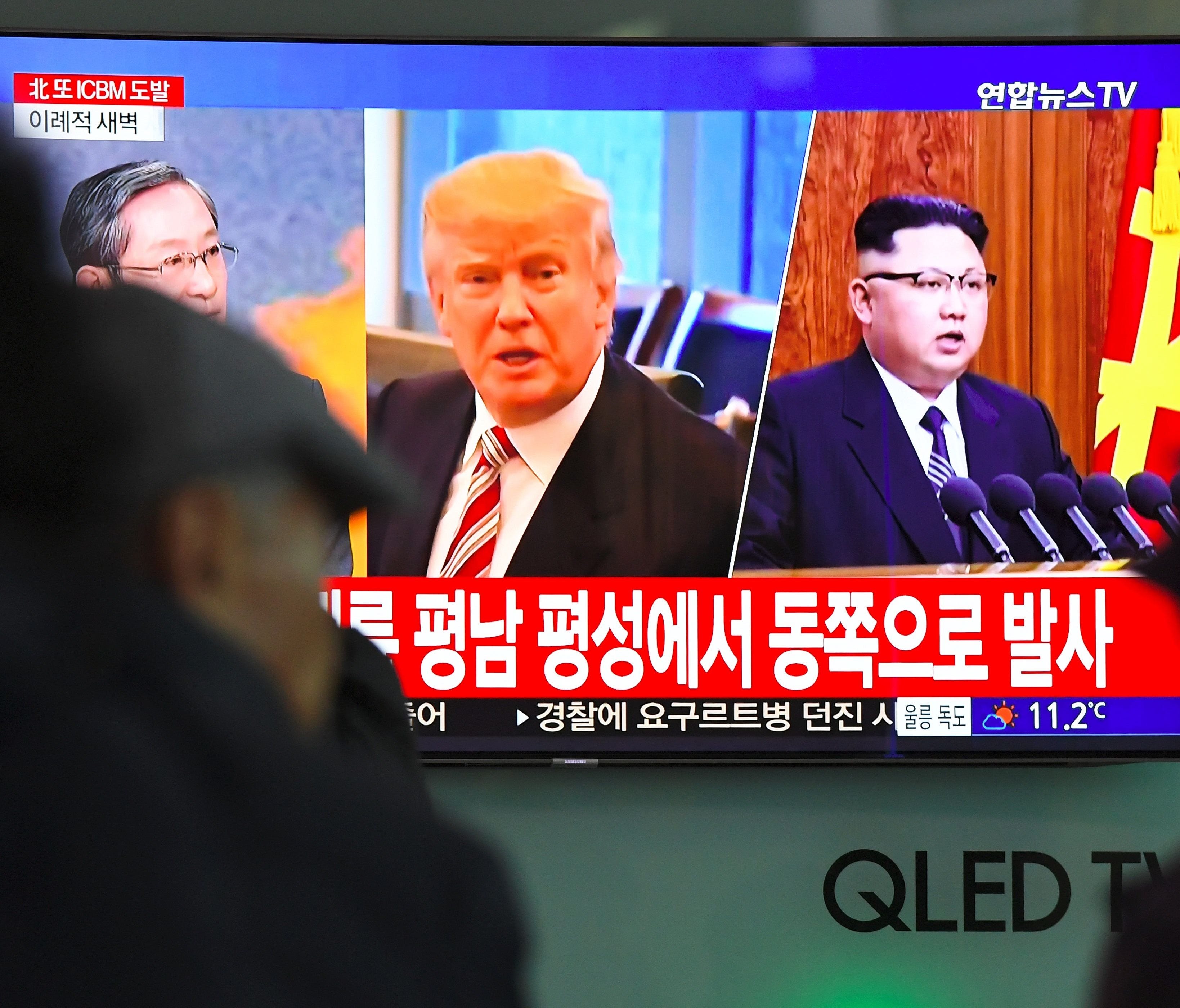 People watch a television news screen showing pictures of President Trump and North Korean leader Kim Jong Un at a railway station in Seoul on Nov. 29, 2017.