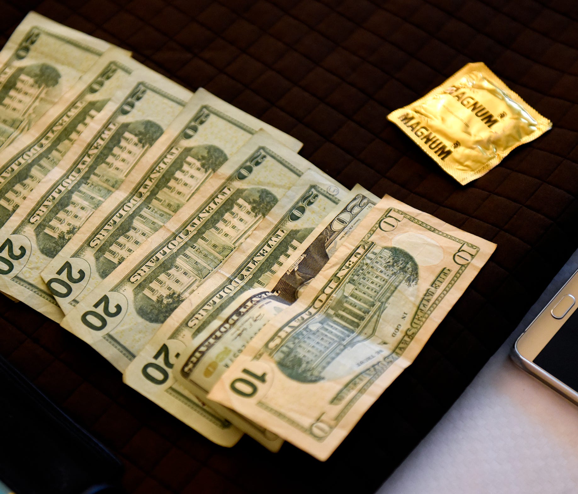 Money and a condom confiscated from a suspected sex buyer are photographed as evidence by members of the Central Minnesota Sex Trafficking Task Force during a June 3, 2016, sting at a St. Cloud hotel.