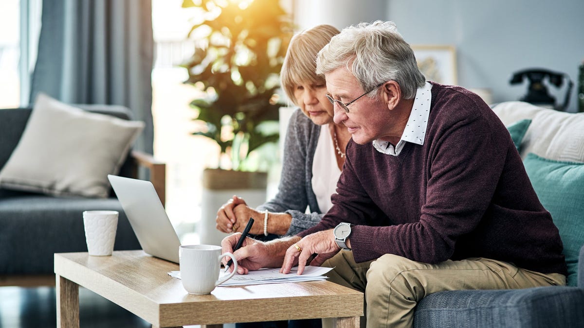 Senior couple sitting on a couch looking at a laptop