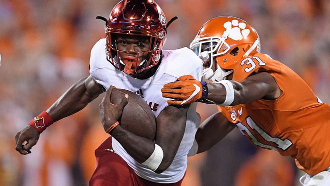 CLEMSON, SC - OCTOBER 01: Lamar Jackson #8 of the Louisville Cardinals looks to avoid the tackle of Ryan Carter #31 of the Clemson Tigers during the fourth quarter at Memorial Stadium on October 1, 2016 in Clemson, South Carolina.  (Photo by Grant Halverson/Getty Images) ORG XMIT: 659650717 ORIG FILE ID: 611919510