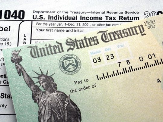 A federal tax refund check lying atop a 1040 tax return.