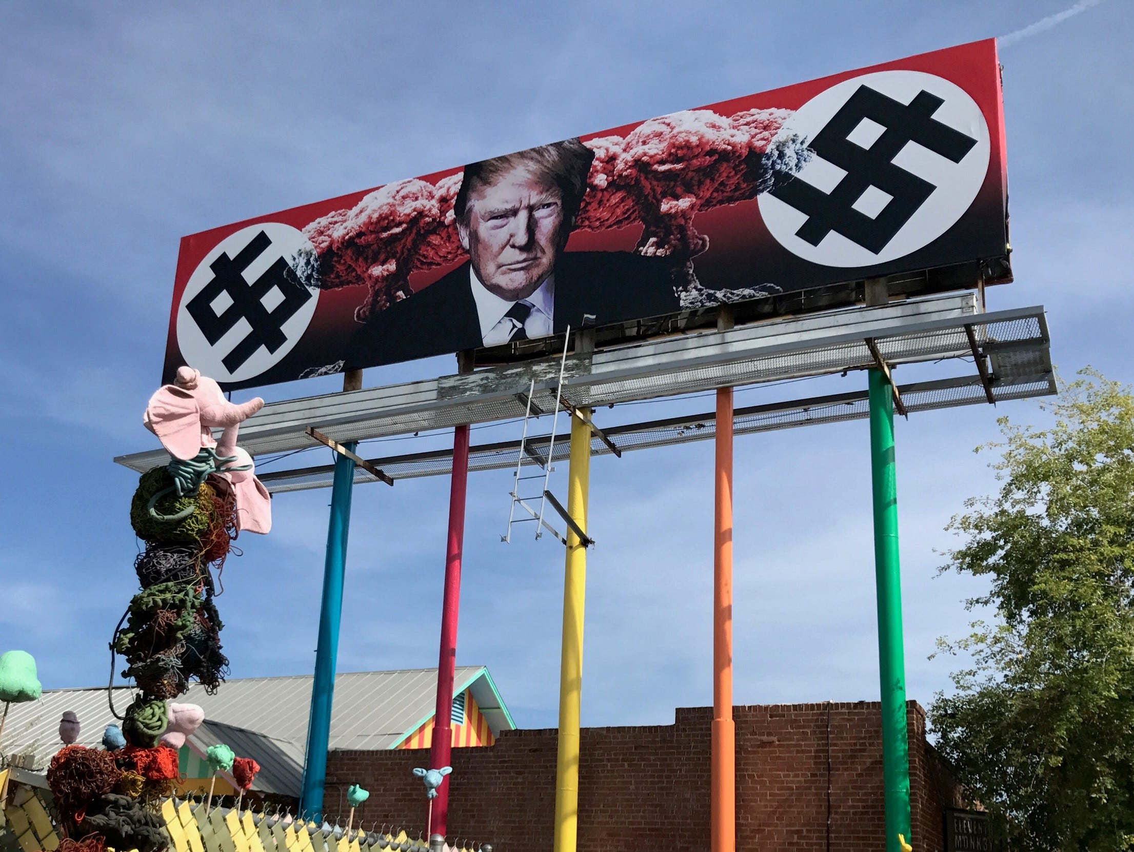 A billboard sign depicting President Donald Trump's face next to explosions and dollar signs created with typography imitating Nazi swastikas went up in downtown Phoenix on March 17, 2017.