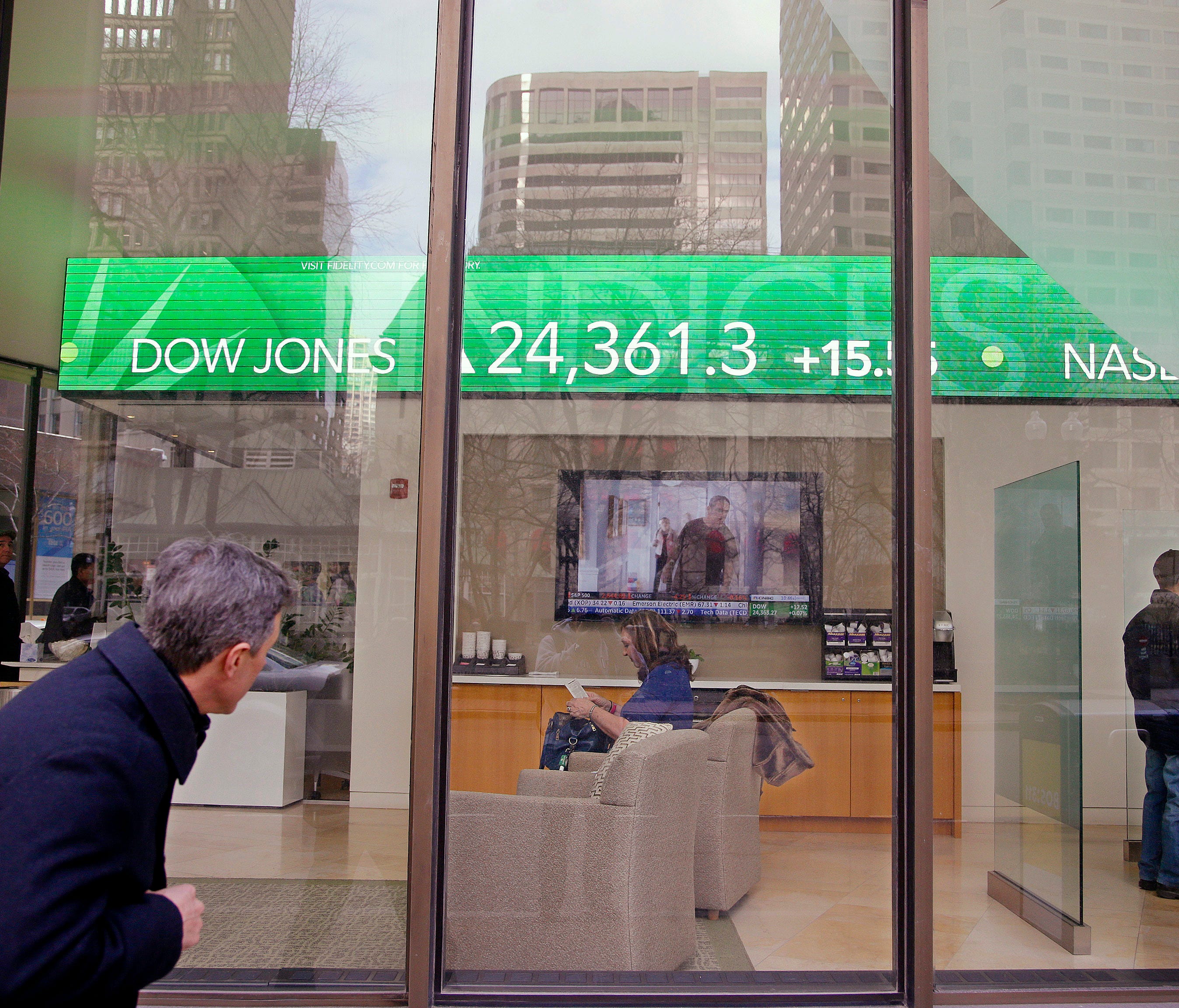 A passer-by peers in the window while investors congregate inside at the Fidelity Investments office on Congress Street as the ticker displays stock market numbers in Boston. A plunge in stock prices always stings, but this recent one dug deeper beca