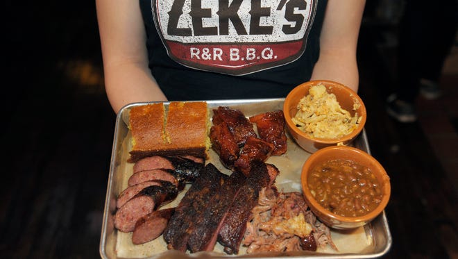 A server presents the four-meat combo plate of rib tips, spare ribs, pulled pork and zekewurst.