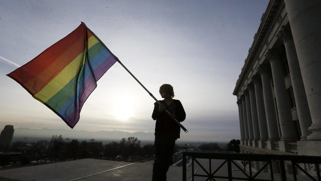 Gay-marriage supporter Corbin Aoyagi waves a rainbow flag Jan. 28 during a rally at the Utah State Capitol in Salt Lake City. A federal judge Friday struck down Alabama’s ban on same-sex marriage, saying it violated couples’ equal protection and due process rights.