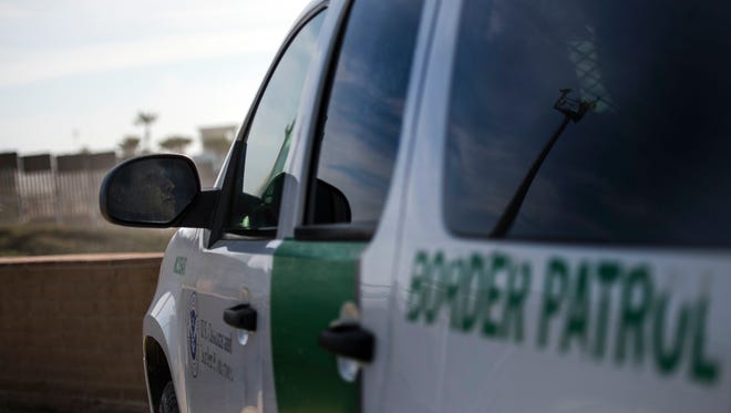 FILE - An US Border Patrol officer sits in his vehicle watching the fence line.