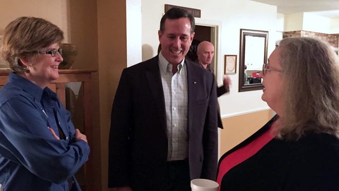 Rick Santorum, center, talks with Jeane Bishop, left, and Nancy Morgan at Bishop’s home in West Des Moines on Monday night.