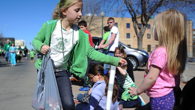 Sophie McElroy, 9, of Sioux Falls, hands CharleeAnn Winter, 3, of Canton, S.D., a piece of candy during the 36th annual St. Patrick's Day Parade on Saturday, March 14, 2015, through downtown Sioux Falls, S.D. 