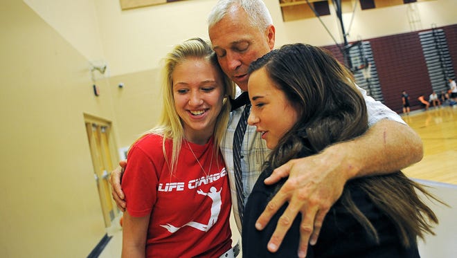 Kevin Lein, principal of Harrisburg High School, gets a hug from Mariah Spotanske, left, and Sophie Schoepf, both 14 and Harrisburg High School freshman, Friday, Oct. 2, 2015, at Harrisburg High School in Harrisburg, S.D., just days after he was shot.