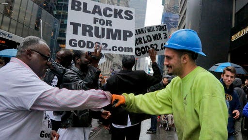 A construction worker exchanges a fist pound with a demonstrator, as pro-Trump supporters gather to cheer his election as President outside Trump Tower.