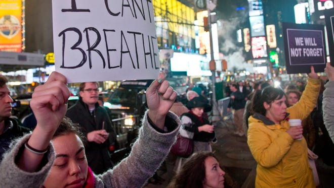 Protesters in Times Square carry signs in reaction to a non indictment against a police officer in the death of Eric Garner, Wednesday Dec. 3, 2014 in New York.