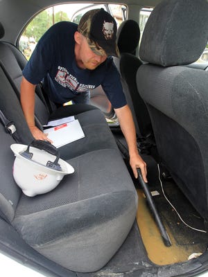 Shaun Chandler, who lives in the 300 block of Covert Run Pike in Bellevue, vacuums water from the floor of the back seat of his Toyota Corolla.
