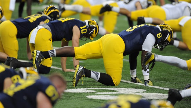 Michigan tight end Tyrone Wheatley Jr. (8)  stretches with fellow players during team practice at Ford Field.