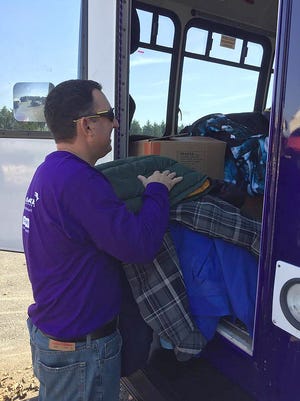 A volunteer loads coats into the Code Purple bus on Monday during a drive put on by Chesapeake Utilities. The company sponsored a drive within all of their offices in the Delmarva area.
