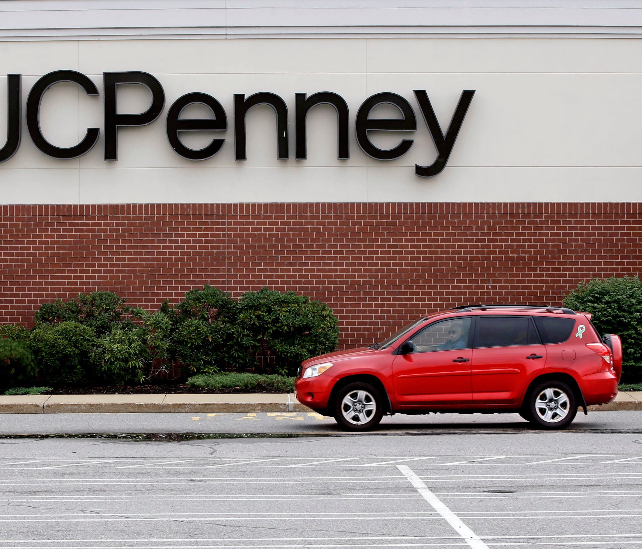 In this Friday, July 10, 2015 photo, a car drives through an empty JC Penney department store parking lot at the Hanover Mall in Hanover, Mass. J.C. Penney Co. reports quarterly financial results on Friday, Aug. 14, 2015. (AP Photo/Stephan Savoia) OR